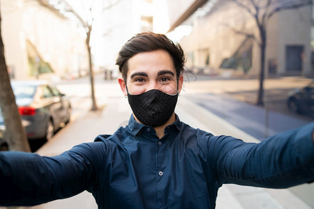 年轻人在街上站着时穿保护面罩和自拍的肖像新正常生活方式概念年轻人在户外自拍的肖像图片