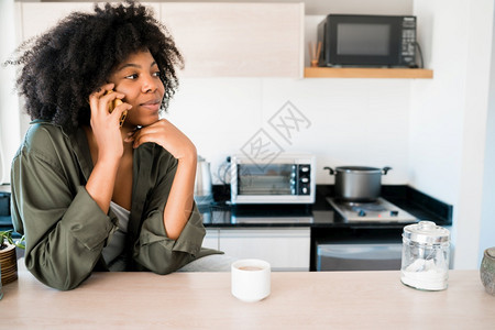 afro女人在电话上聊天家里喝杯咖啡交流概念在家里电话上聊天的afro女人的肖像图片