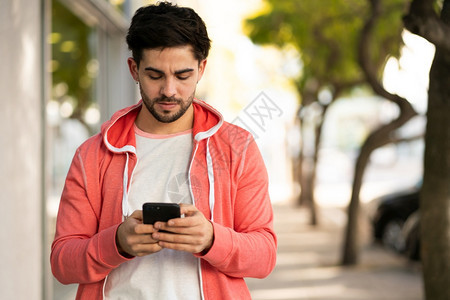 年轻人在街上户外散步时使用手机的肖像图片