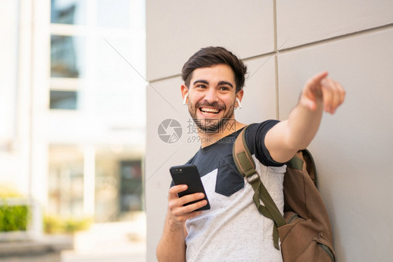 年轻人使用手机的肖像指向户外的东西城市概念图片