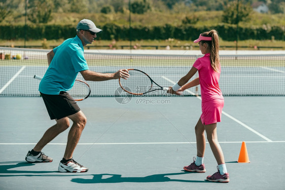 网球训练中与年轻女孩一起参加网球训练的教官图片
