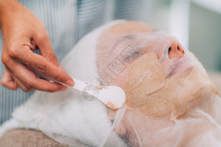基于蔬菜的面部水合罩美容学家将罩应用到妇女脸部水合面罩美容沙龙的蔬菜面部治疗上图片