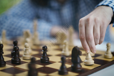 正在玩象棋一位男象棋玩家的手移动白色象棋块玩家的手移动象棋一块图片