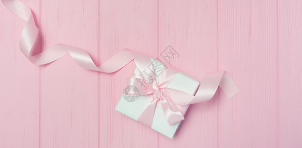 带有粉红色木质背景带丝的礼品盒并有您文本的位置以情人节母亲日或生为主题顶部视图平躺带有丝的横幅礼品盒粉红色木质背景为您文本的位置图片