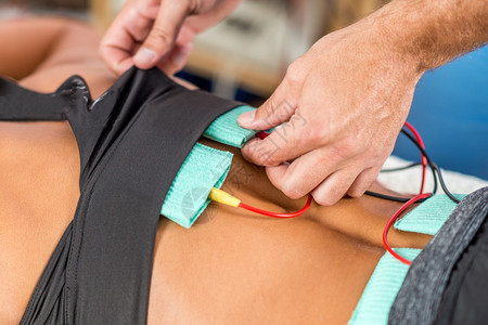 理疗师将电极定位在女运动员和身上图片