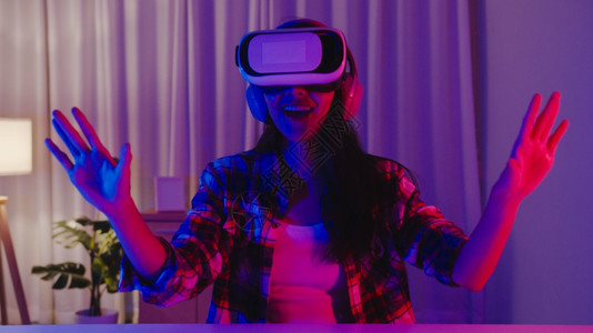 Asia女士戴着快乐的游戏头盔拥有可穿戴的乐趣体验穿戴虚拟提升现实数字创新科技年一的夜宴节庆祝活动快乐时刻在家客厅举行晚宴庆祝活图片