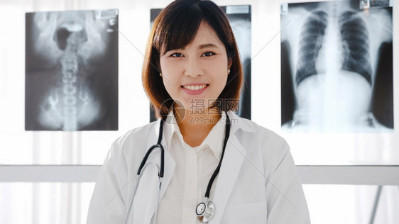 身穿白色医疗制服有听诊器的年轻女医生看着相片微笑图片