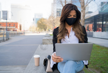 女在户外使用笔记本电脑时佩戴保护面罩城市概念新的正常生活方式概念图片