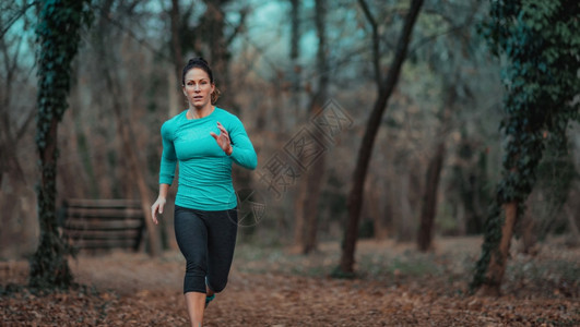 女运动员在公园慢跑秋天自然妇女慢跑公园图片