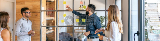 工作会议中的商人站在墙上贴粘纸条集思广益的概念在墙上贴粘纸条图片
