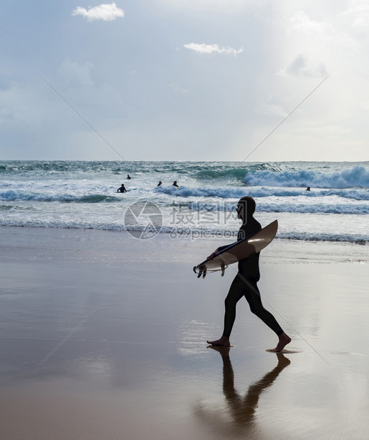 海滩上冲浪者带板的背影图片