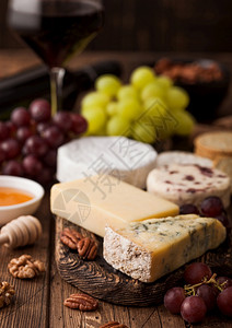 玻璃红葡萄酒在木制桌底选择各种奶酪和葡萄图片