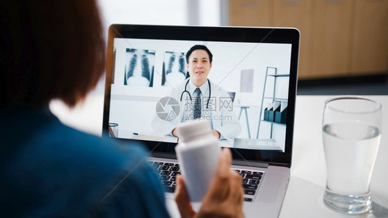 使用电脑笔记本的年轻女士在视频电话中谈论一种疾病在家中客厅与资深医生进行在线咨询图片