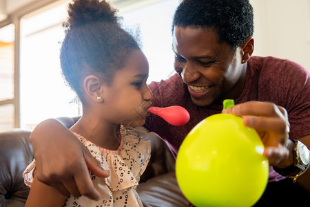 女儿和父亲一起玩乐在家里气球的肖像图片