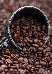 咖啡豆背景中黑色陶瓷杯的新鲜咖啡豆图片