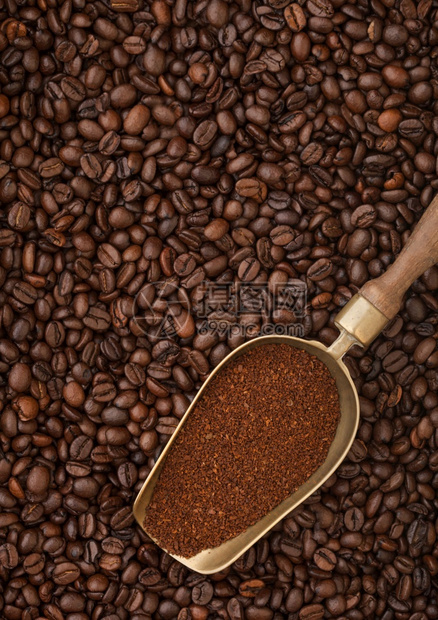 咖啡豆背景的旧钢勺中新鲜烤咖啡粉图片