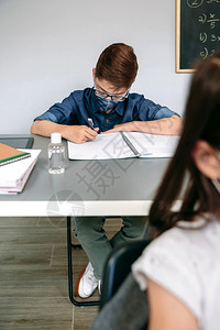 在学校的笔记本上写着面罩的男孩图片