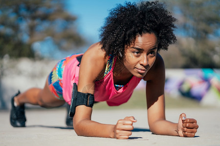 afro运动女在户外的地板上做俯卧撑运动和健康的生活方式概念图片