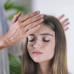 女抗逆转录治疗师的横向形象站在美丽的十几岁病人头上举起手来抗逆转录治疗师移能量图片
