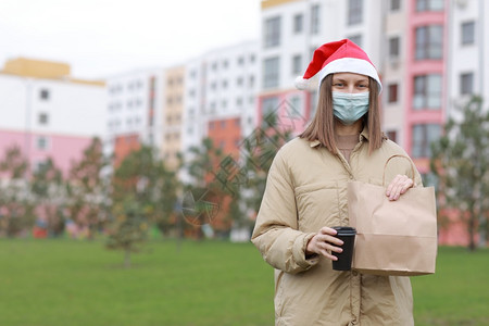 戴保护面罩和sant戴帽子的女童携带纸袋装有产品和咖啡的户外戴保护面罩和sant戴保护面罩和sant戴保护面罩的女童携带纸袋装有图片