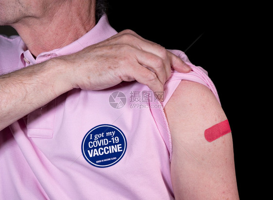 高大成人男子用粘贴着纸用粘在19号疫苗上展示他的粘贴膏表示他得到了疫苗高大男子在19号疫苗上展示粘贴绷带图片