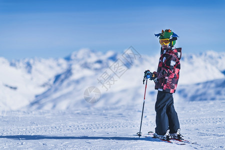 穿多彩服装的年轻男子在山顶上滑雪图片
