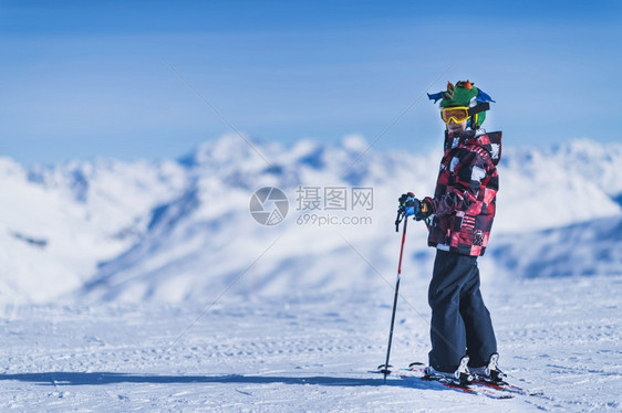 穿多彩服装的年轻男子在山顶上滑雪图片