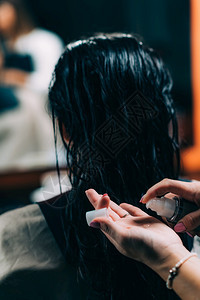 将恢复的油滴应用到妇女身上的理发师和长的黑头发型师将恢复的油滴应用到妇女身上理发师图片