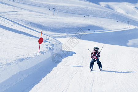 活跃的十几岁小孩带着安全头盔护目镜和滑雪杆跑下坡景冬季阳光明媚的天气山上滑雪背景图片
