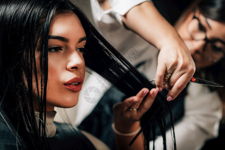 女美发师在廊剪刀她的长发黑美容师在理店图片