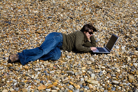 在海滩上工作的年轻女子笔记本电脑工作图片