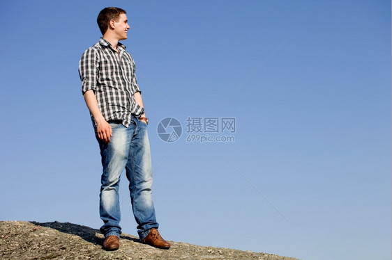 年轻男子在岩石顶上图片
