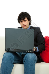 青年男子在沙发上用笔记本电脑工作图片