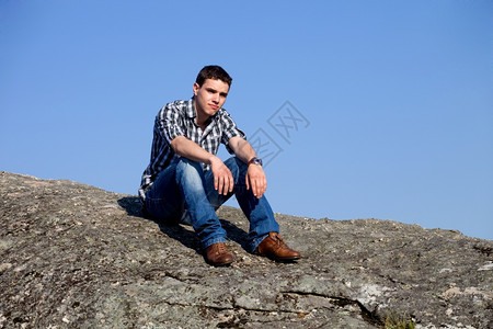 年轻在岩石顶上天空是背景图片