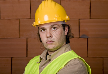 骑车带安全帽带黄帽子的工头用砖墙作为背景背景