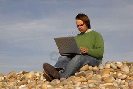 海滩上拿着笔记本电脑的青年男图片