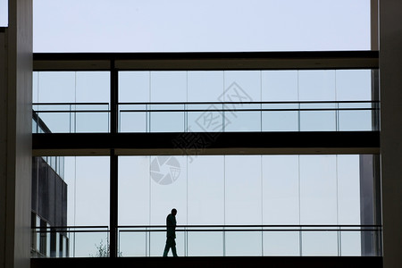 年轻商人在现代办公楼内用全景窗走动的影视背景图片
