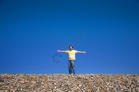 男人在海滩上张开双臂图片