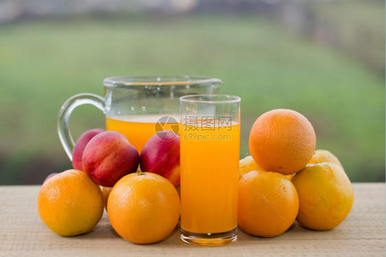 在户外木制桌上的橙汁和桃子杯图片