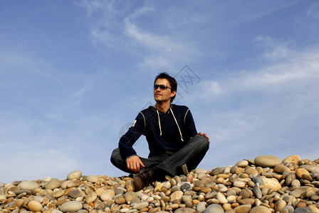 海滩石头边的青年背景图片