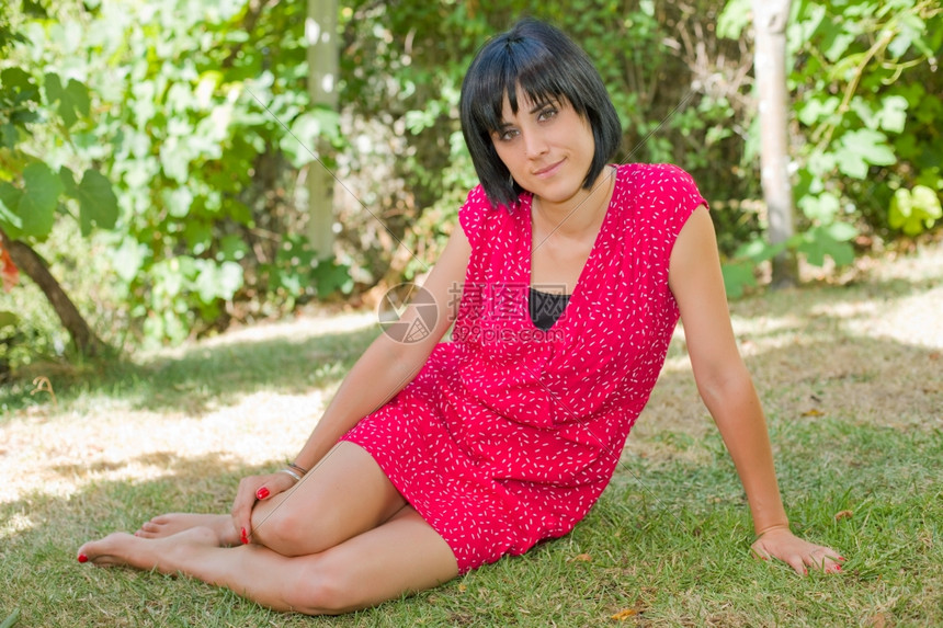 年轻的临时女青坐着对镜头微笑户外高清图片下载-正版