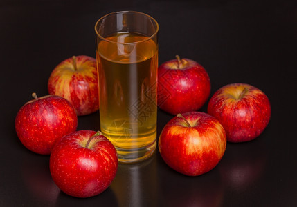 苹果汁和深木背景上的红苹果图片