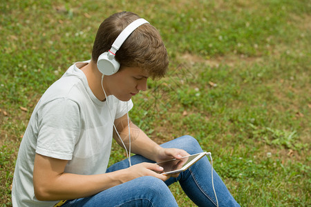 年轻人在公园户外与平板电脑一起放松听音乐和耳机图片