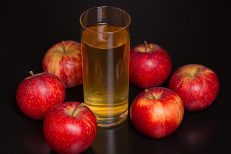 苹果汁和深木背景上的红苹果图片