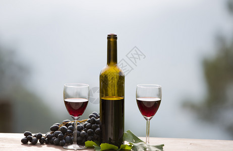 酒瓶和葡萄放在户外的木桌上红酒图片
