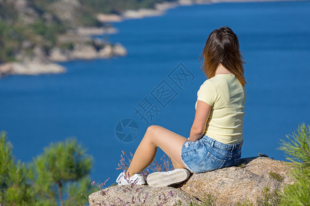 在山上快乐的年轻女子放松和享受湖在泽鲁古公园的Gers图片