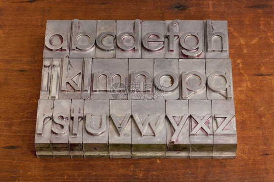 以古老的纸质印刷金属块和木背景的英文字母表图片