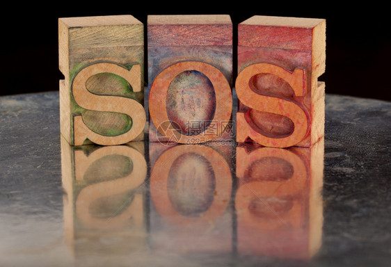 求助呼叫概念旧木纸质印刷板中的SOS字面有反光的木纸质印刷板图片