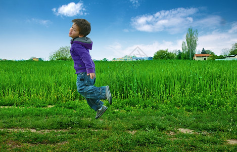 在绿色草原上跳男孩蓝天草地图片