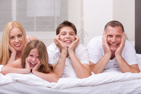 美丽的家庭躺在床上微笑地看着镜头图片